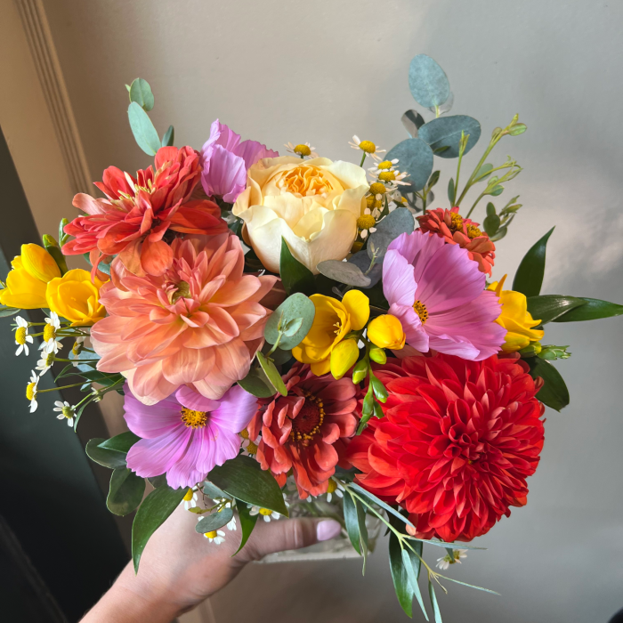 A medium custom vase arrangement with red, purple and peach flowers.